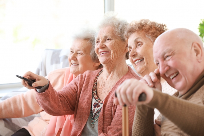 Group of elderly people laughing and smiling watching TV