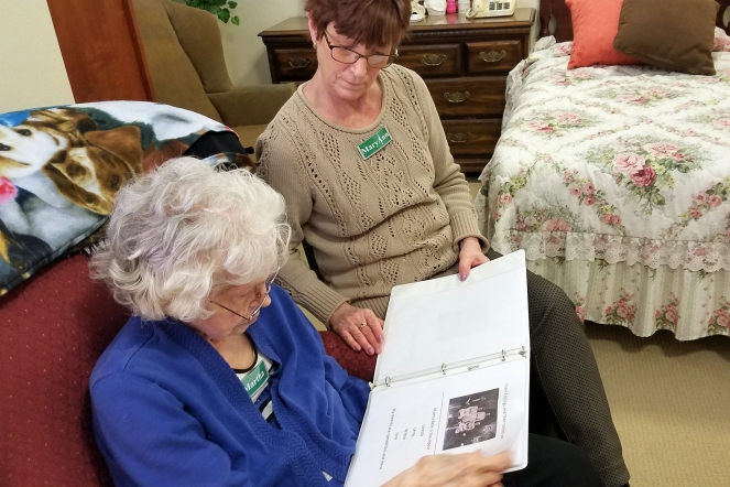 Elderly woman and carer reading memory book